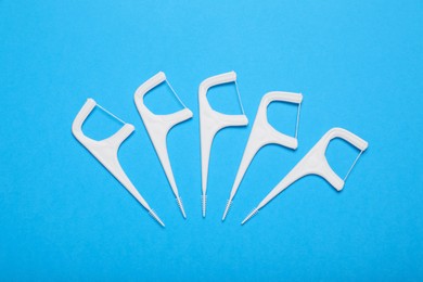 Dental flossers on light blue background, flat lay