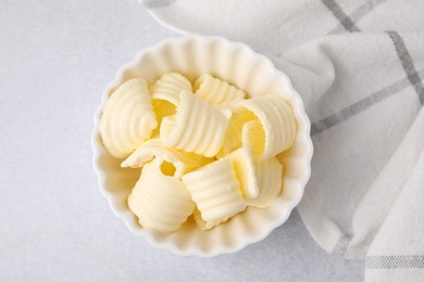 Photo of Tasty butter curls in bowl on light grey table, top view
