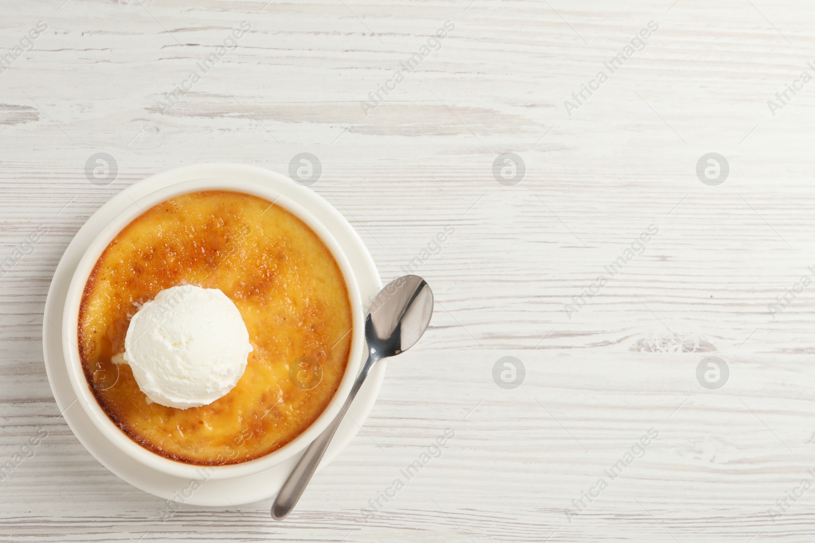 Photo of Delicious creme brulee with scoop of ice cream and spoon on white wooden table, top view. Space for text