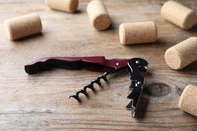 Photo of Opener with corkscrew and corks on wooden table