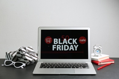 Photo of Composition with laptop and gifts on table against white background. Black Friday sale