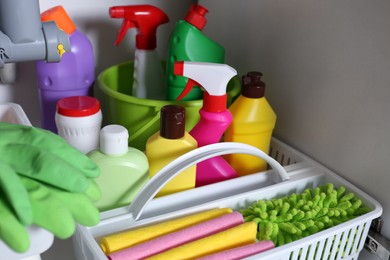 Open under sink cabinet with different cleaning supplies in kitchen, closeup