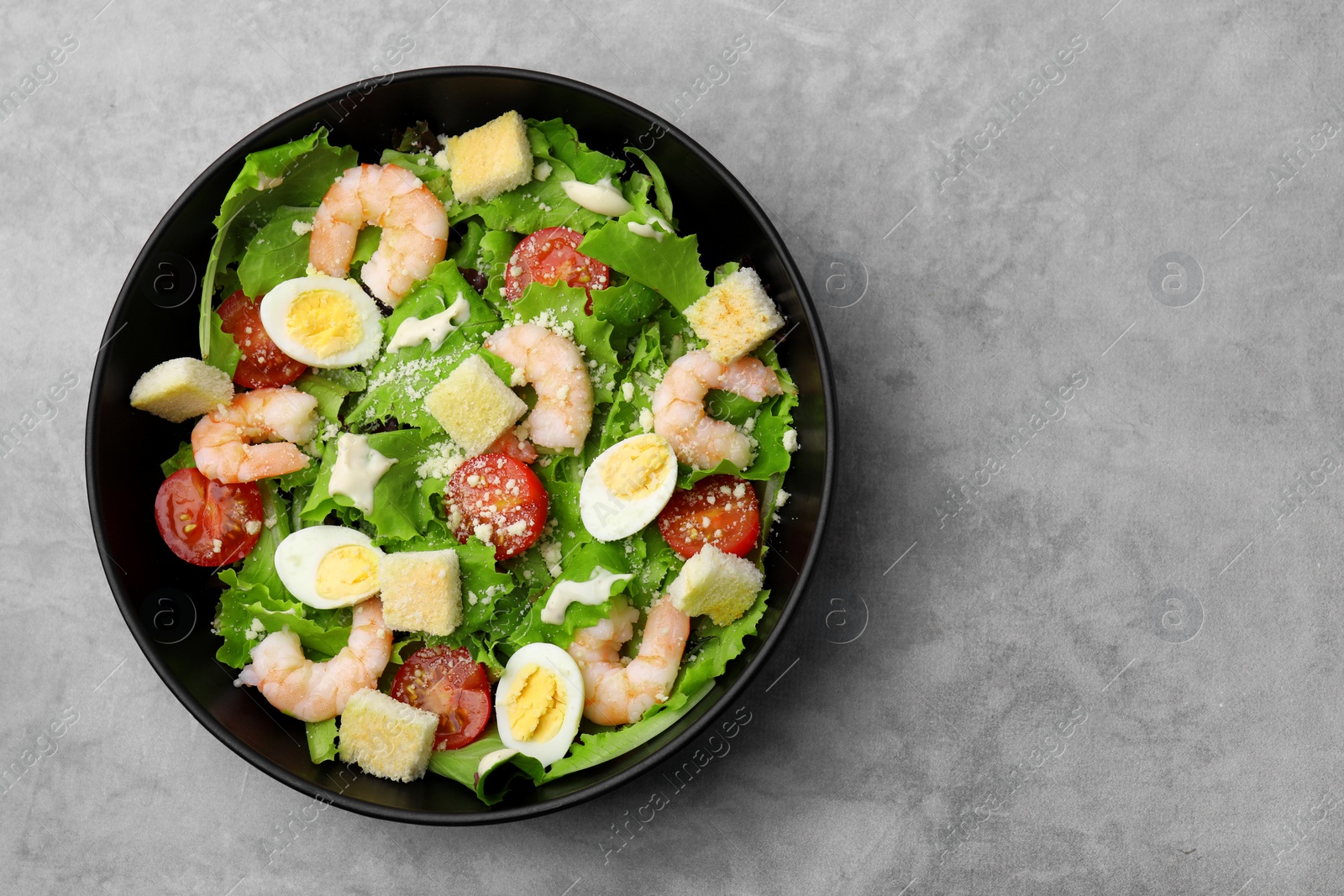 Photo of Delicious Caesar salad with shrimps on grey table, top view. Space for text