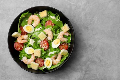 Delicious Caesar salad with shrimps on grey table, top view. Space for text