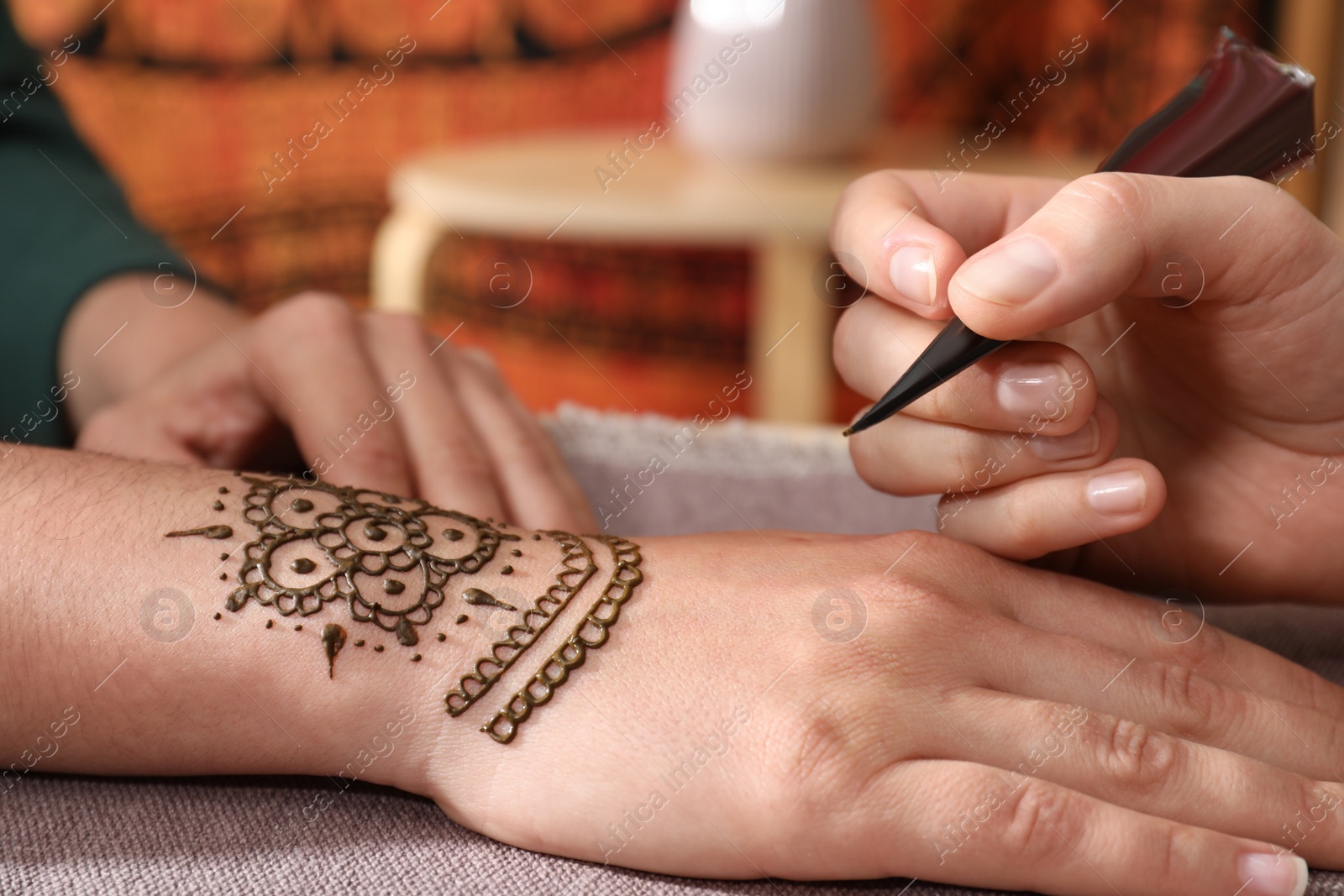 Photo of Master making henna tattoo on hand, closeup. Traditional mehndi