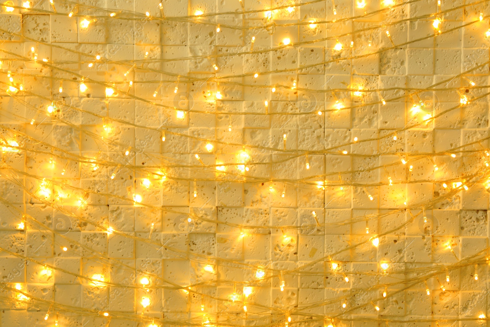 Photo of Christmas lights hanging on beige stone wall