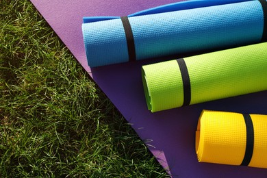 Photo of Bright exercise mats on fresh green grass outdoors, above view