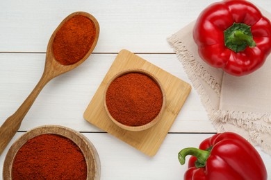 Photo of Bowls, spoon with aromatic paprika powder and fresh bell peppers on white wooden table, flat lay