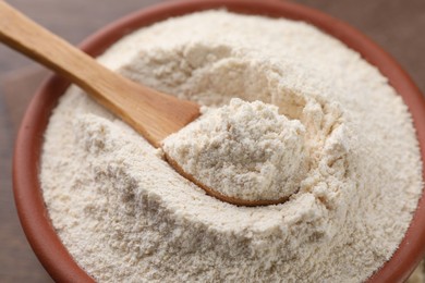 Photo of Wooden bowl and spoon with quinoa flour, closeup