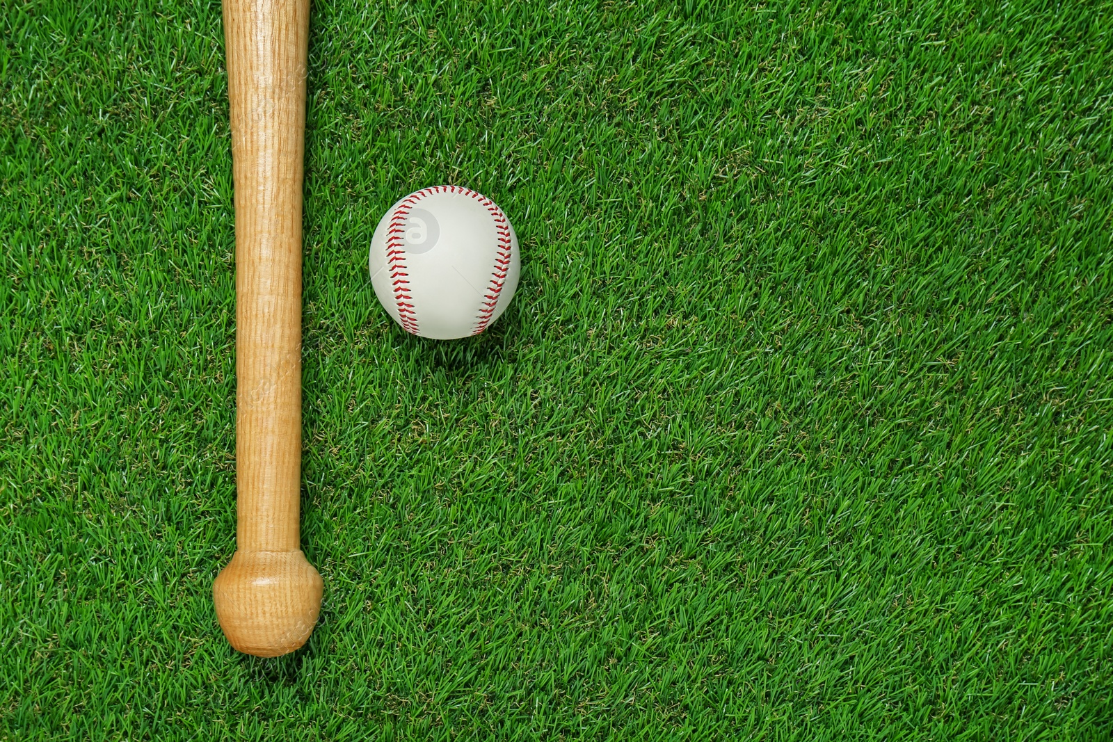 Photo of Wooden baseball bat and ball on green grass, flat lay. Space for text