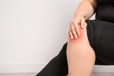 Overweight woman on light background, closeup of legs