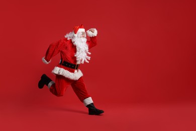 Photo of Merry Christmas. Santa Claus running on red background, space for text