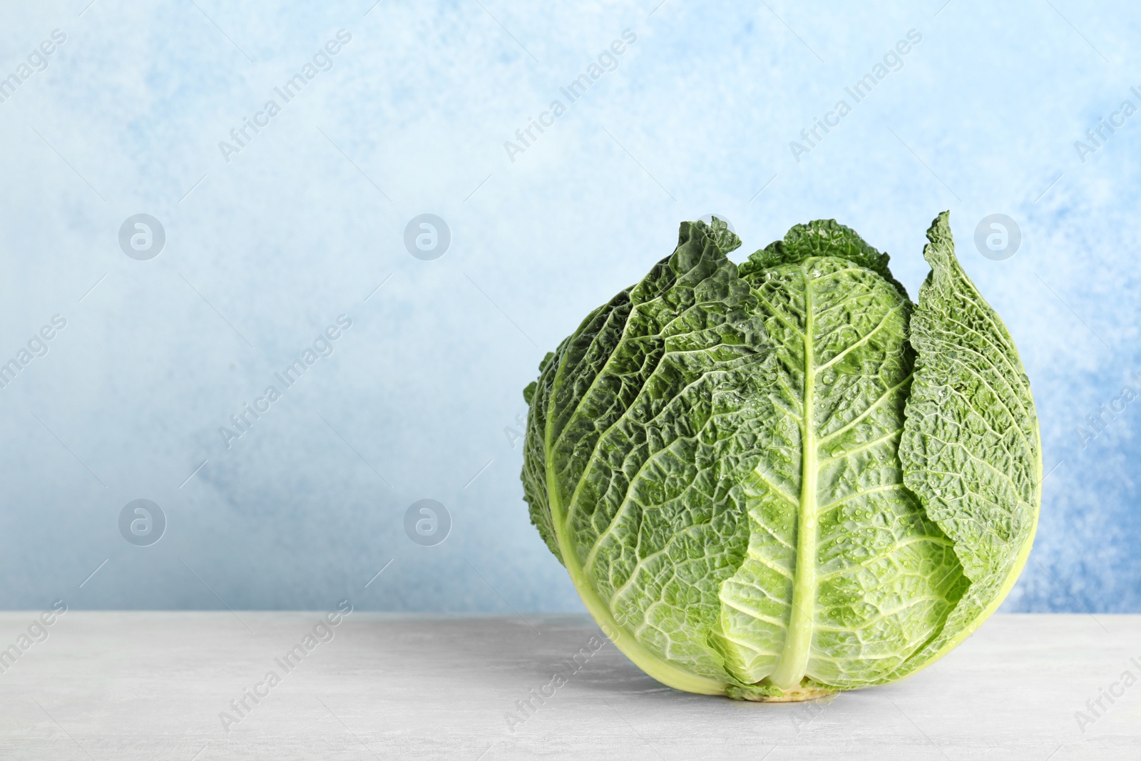 Photo of Savoy cabbage on table against color background. Space for text