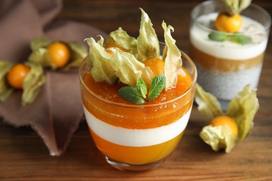 Delicious dessert decorated with physalis on wooden table, closeup