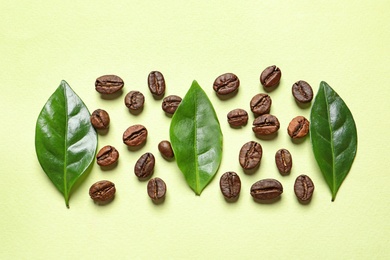 Photo of Fresh green coffee leaves and beans on light green background, flat lay