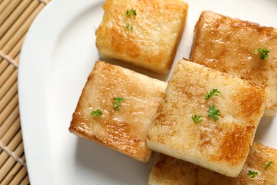 Photo of Ceramic plate with delicious turnip cake on bamboo mat, closeup