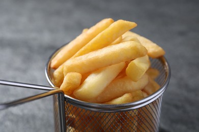 Photo of Frying basket with tasty french fries on light grey background, closeup