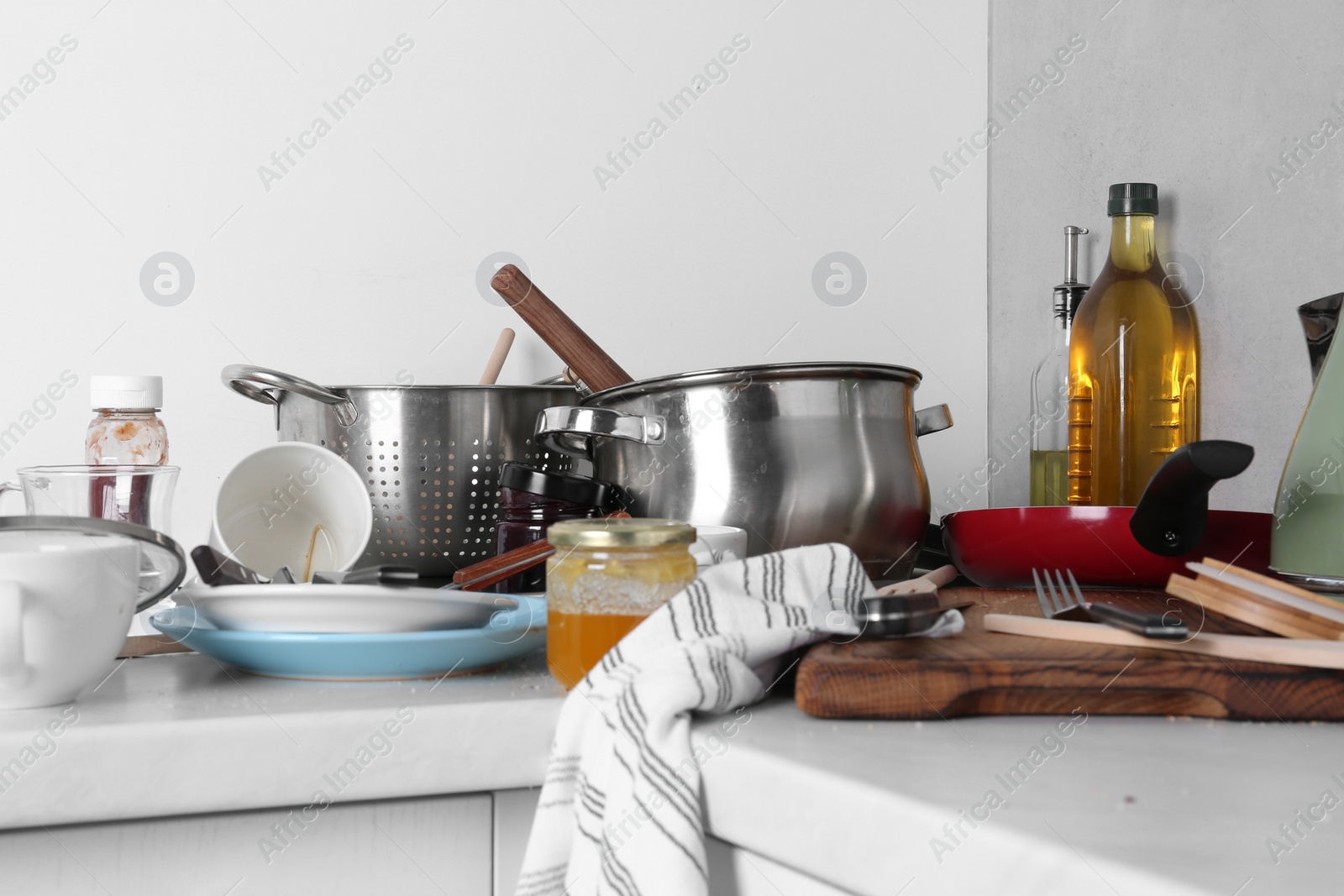 Photo of Many dirty utensils, cookware and dishware on countertop in messy kitchen