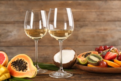 Photo of Delicious exotic fruits and glasses of wine on wooden table