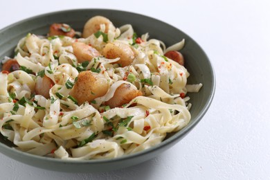 Delicious scallop pasta with spices in bowl on white table, closeup