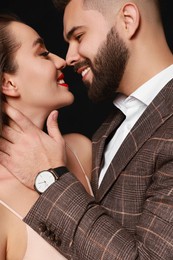 Photo of Handsome bearded man with sexy lady on black background, closeup
