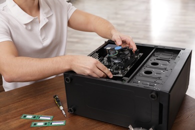 Male technician repairing computer at table indoors, closeup