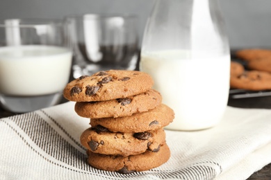 Stack of tasty chocolate chip cookies and milk on table