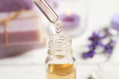 Photo of Dripping lavender essential oil into bottle, closeup