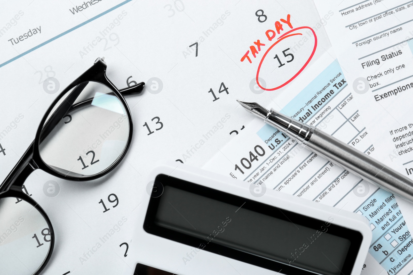 Photo of Tax day. Calendar with date reminder, documents, pen, glasses and calculator on table, flat lay