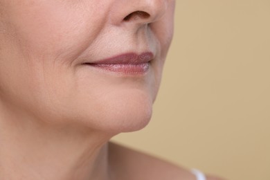 Photo of Senior woman with aging skin on beige background, closeup and space for text. Rejuvenation treatment