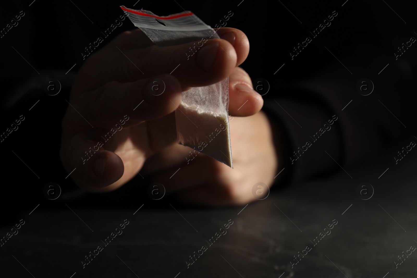 Photo of Drug addiction. Man with plastic bag of cocaine at grey table, selective focus