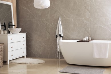 Photo of Modern white tub and chest of drawers with sink in bathroom. Interior design