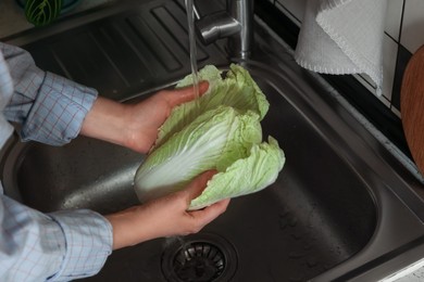 Woman washing fresh Chinese cabbage in sink, closeup