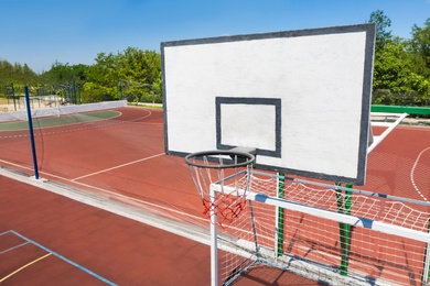 Image of Basketball backboard over football gat at outdoor sports complex on sunny day