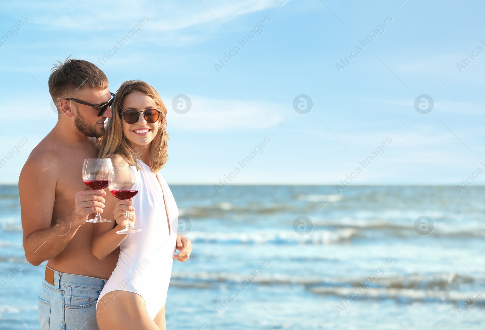 Photo of Young couple with glasses of wine on beach