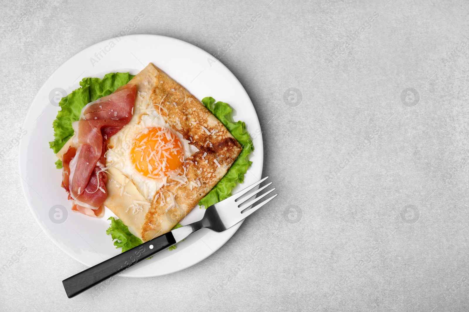 Photo of Delicious crepe with egg served on light gray table, flat lay with space for text. Breton galette