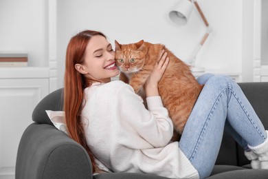 Photo of Happy woman with her cute cat on sofa at home