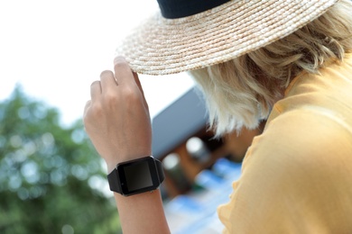 Woman wearing modern smart watch outdoors, closeup
