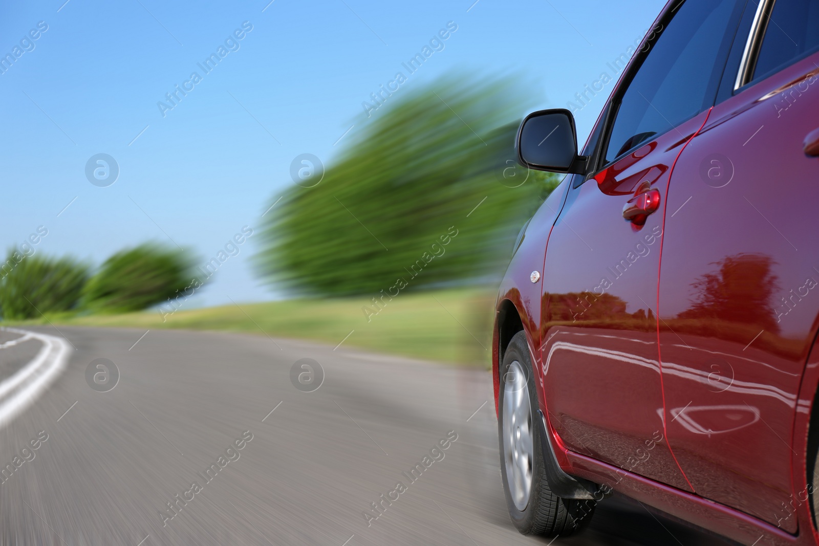 Image of Red car driving at high speed on asphalt road outdoors, closeup with motion blur effect. Space for text