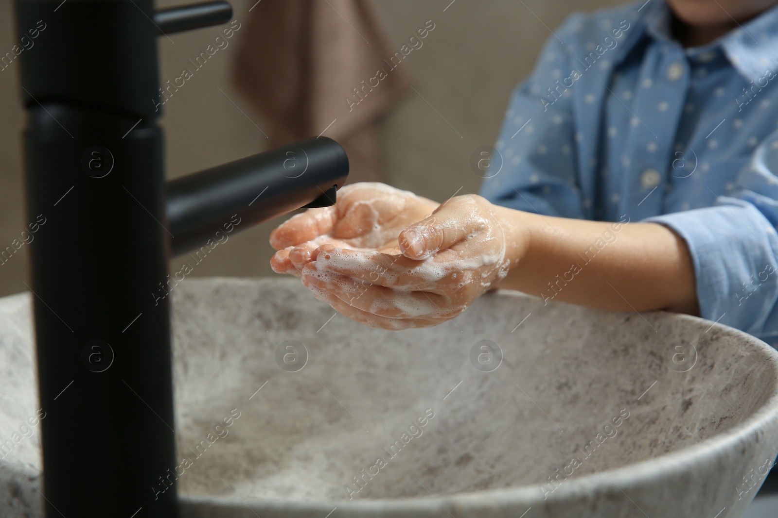 Photo of Little girl washing hands with liquid soap in bathroom, closeup