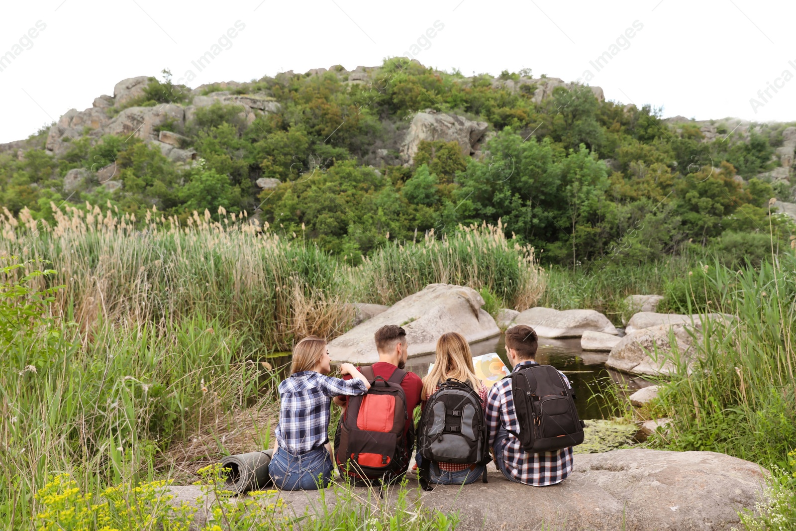 Photo of Young people exploring map in wilderness. Camping season