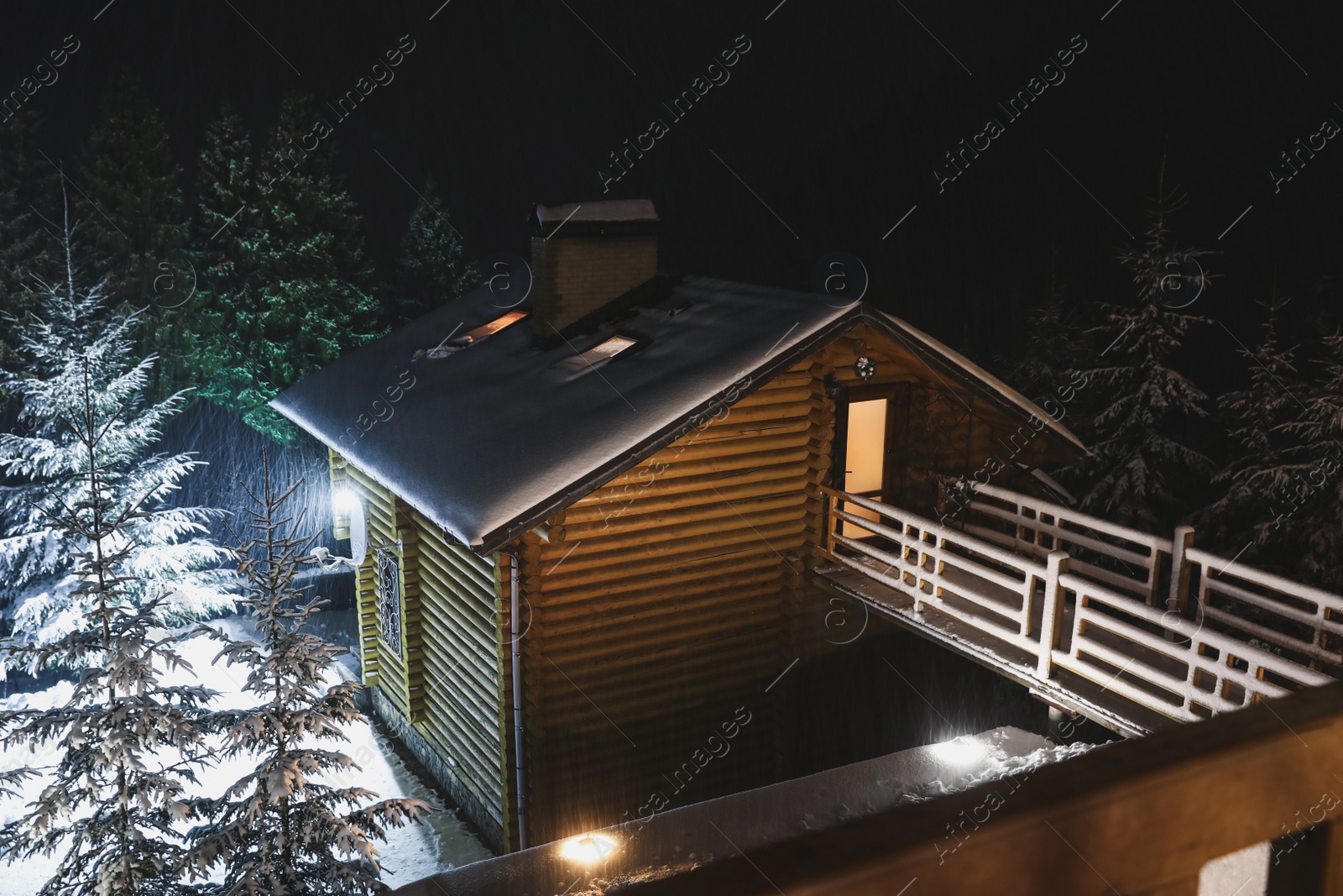 Photo of Wooden cottage with snowy yard at night, above view. Winter vacation