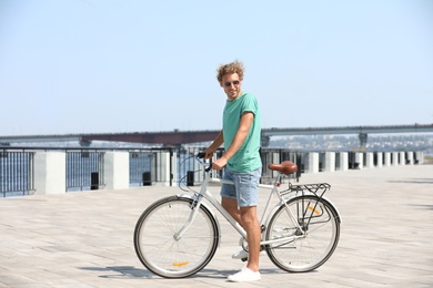 Handsome young man with bicycle outdoors on sunny day