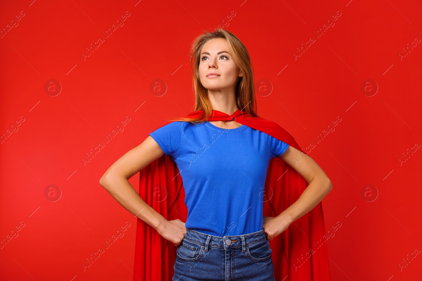 Photo of Confident woman wearing superhero cape on red background