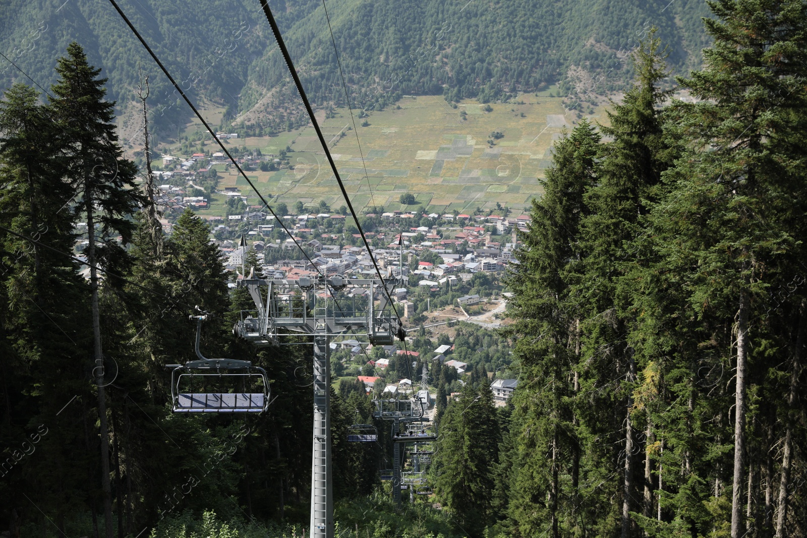 Photo of Picturesque view of beautiful trees and cableway with seats