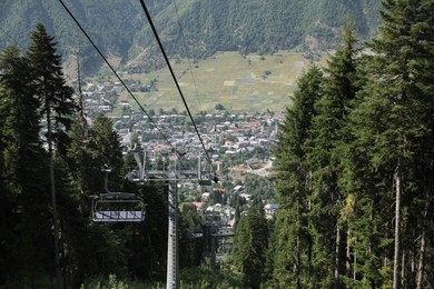 Photo of Picturesque view of beautiful trees and cableway with seats