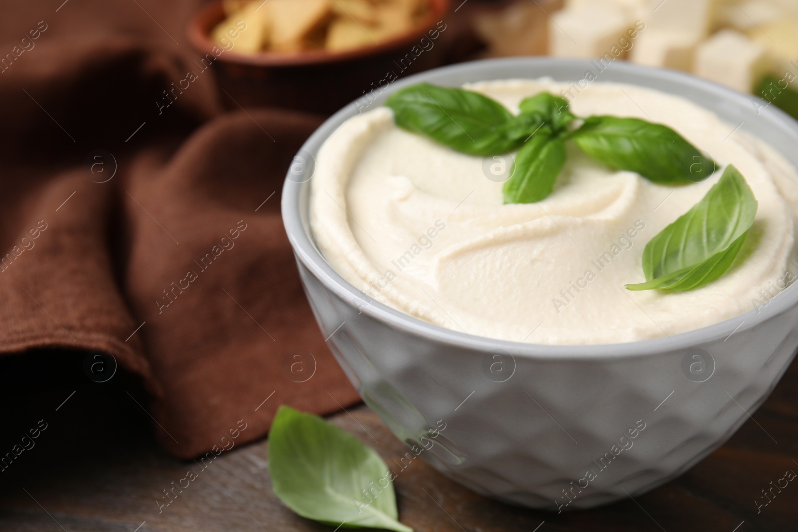 Photo of Delicious tofu sauce and basil leaves in bowl on wooden table, closeup. Space for text