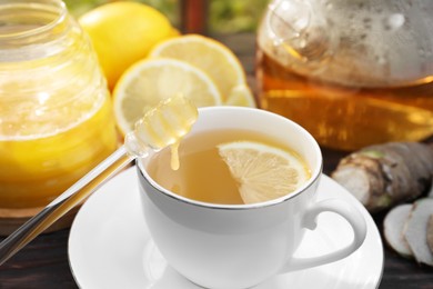 Photo of Cup of delicious tea with lemon and honey on wooden table, closeup