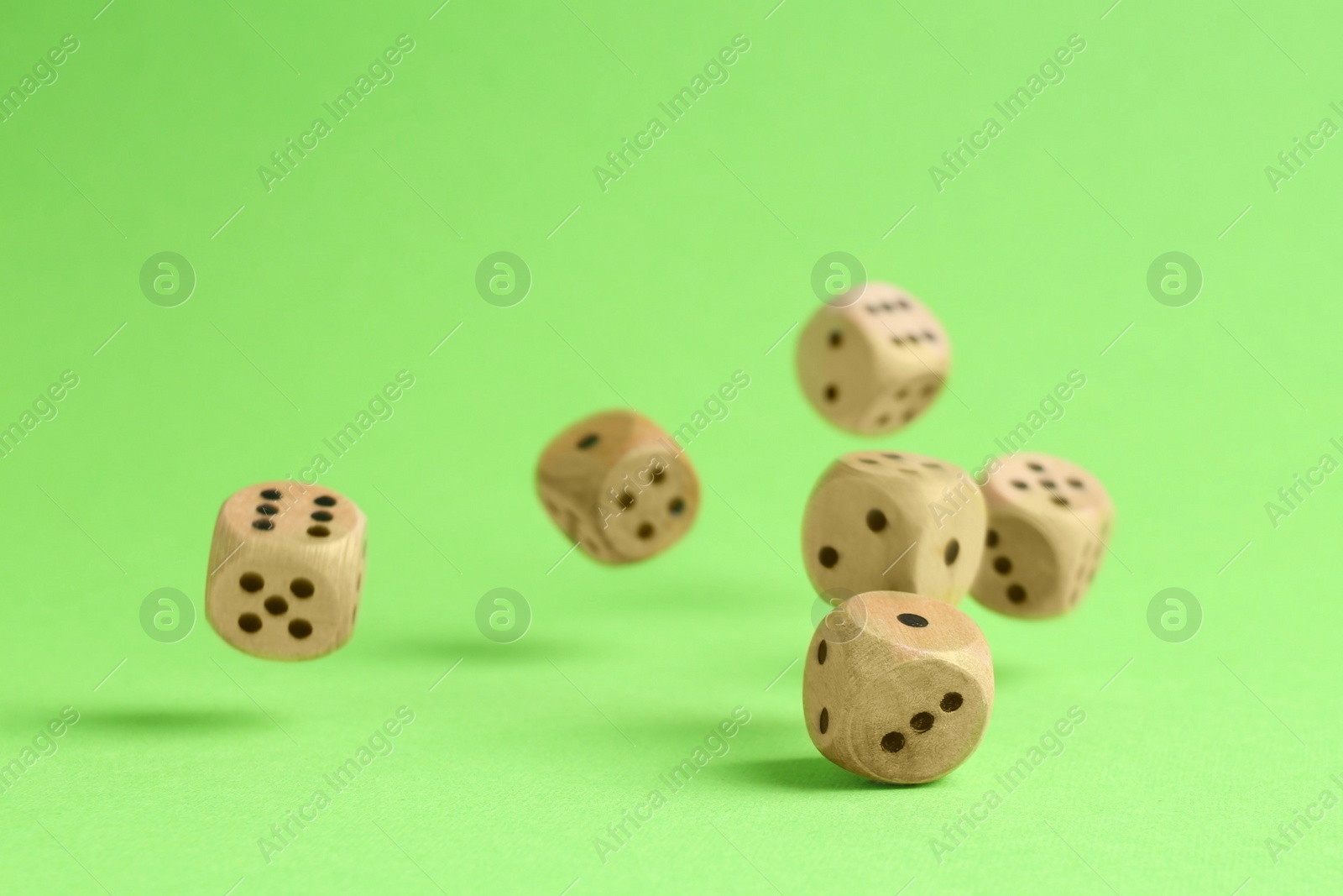 Photo of Many wooden game dices falling on green background