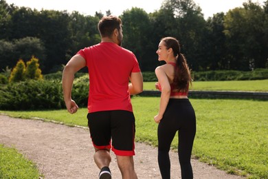 Photo of Healthy lifestyle. Couple running in park on sunny day, back view